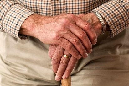 An elderly man leaning on his cane.