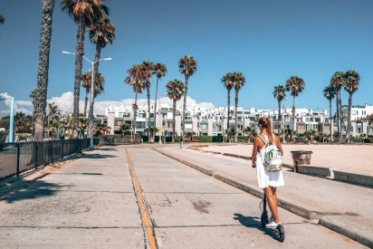Woman riding a scooter in a beach town.