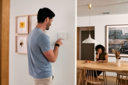 Man adjusting the temperature on his smart thermostat.