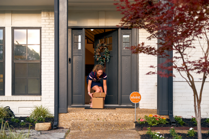 Woman picking up a package from her front porch.