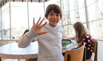 A young boy waving at the camera.