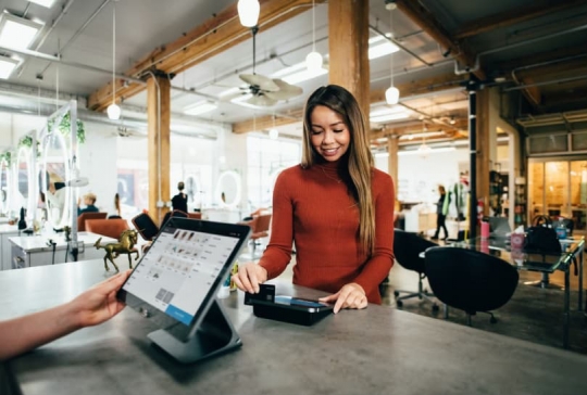 Woman swipes her credit card in order to complete a purchase