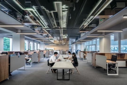 Large workspace with three people using laptops