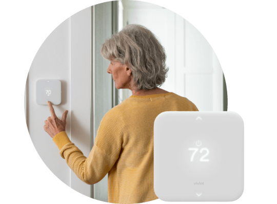 Woman adjusting the temperature on her smart thermostat from Vivint.