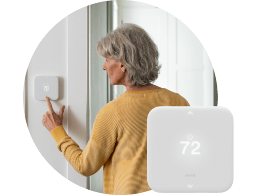 Woman adjusting the temperature on her smart thermostat from Vivint.
