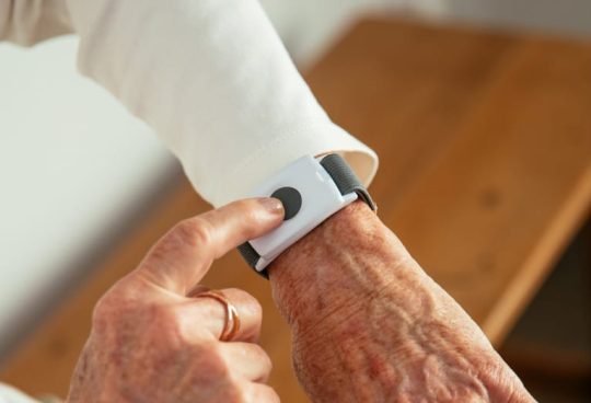 Person pressing button on the emergency pendant bracelet.